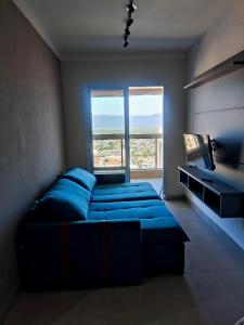 a bedroom with a blue couch and a large window at Residencial Acquamare in Praia Grande +18 photos