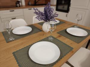 a wooden table with white plates and wine glasses at Sweet Home Sielawy in Poznań +5 photos