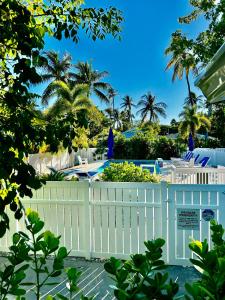 a white fence in front of a pool with palm trees at Castaway Island Vacation Bungalow in Islamorada