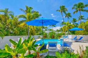 a swimming pool with blue umbrellas and chairs at Castaway Island Vacation Bungalow in Islamorada
