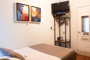 a room with a bed and a tv on a wall at Pórtico Hotel & Galería in Morelia +44 photos