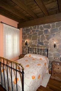 a bedroom with a bed and a stone wall at El Rincon Del Villar in Villar de Plasencia