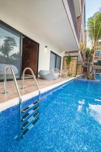 a large swimming pool with blue tiles on the side of a house at Magic Paramar Terra C103 in Aldea Zama Tulum in Tulum