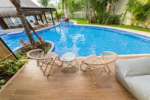 a swimming pool with four chairs and a couch next to it at Magic Paramar Terra C103 in Aldea Zama Tulum in Tulum