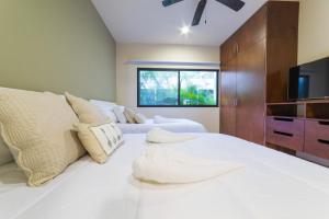 a bedroom with a large white bed and a tv at Magic Paramar Terra C103 in Aldea Zama Tulum in Tulum