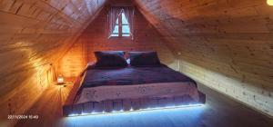 a bed in a wooden room with a window at Vodenica Vrelo Chalets in Vrelo Koreničko