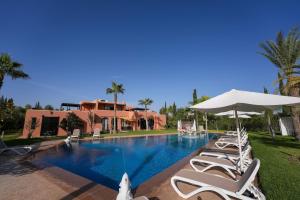 a swimming pool with lounge chairs and an umbrella at Janat Al Atlas Resort & Spa in Marrakech