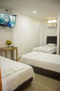 a room with two beds and a flat screen tv at Hotel Boutique Don Polo in San Juan Nepomuceno
