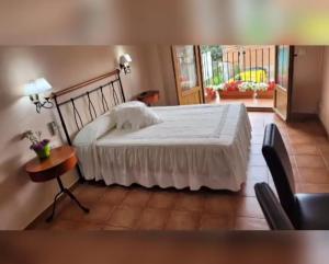 sypialnia z dużym białym łóżkiem i stołem w obiekcie Hotel Rural Cristania w mieście Caminomorisco
