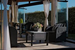 a patio with wicker chairs and a table with flowers at La Veranda Sul Mare Sardegna - Baia delle Mimose in Badesi +45 photos