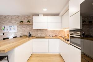 a kitchen with white cabinets and a wooden counter top at Jardinillos Bed & Parking in Jaén