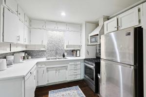 una cucina con armadi bianchi e frigorifero in acciaio inossidabile di Comfy and Modern Holiday Lofts in FW a Fort Worth