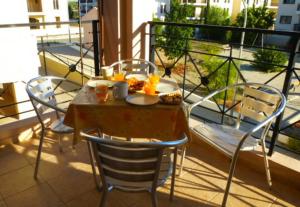 a table and chairs on a balcony with food on it at Mazotos Panoramic Village in Mazotos