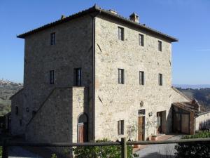 a large stone building with a clock on it's side at Agriturismo Il Casolare Di Bucciano in San Gimignano