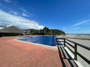 ハマにあるLujoso departamento Jama Manabí con vista al Marのビーチの隣のフェンスの隣にあるスイミングプール
