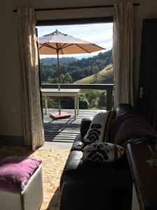 - un salon avec un canapé et un parasol dans l'établissement Chalé Serra do Luar, à Santo Antônio do Pinhal
