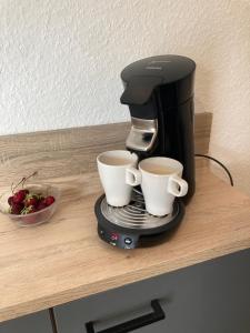 a coffee maker and two coffee cups on a counter at Ferienwohnung Soltau Parkplatz, Dachterrasse, Klimaanlage, 5 Gäste in Soltau