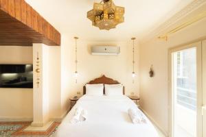 a bedroom with a bed with white sheets and a chandelier at The Majestic Marrakesh Studio Cairo's Downtown 19A in Cairo