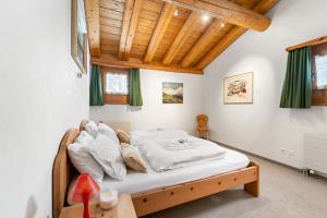 Un dormitorio con una cama con sábanas blancas y techos de madera. en Chalet St Moritz, en Madulain 19 fotos más