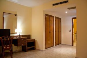 タラベラ・デ・ラ・レイナにあるHotel Peralesのデスク、椅子、鏡が備わる客室です。