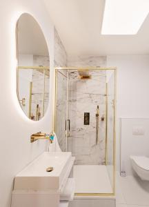 a white bathroom with a shower and a sink at Apartament Ułański - City Park in Poznań
