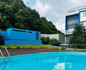 a blue swimming pool in front of a building at Duplex Apartment Ponta Delgada in Fajã de Baixo