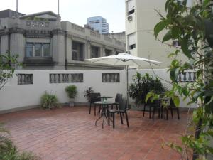 un patio con mesas, sillas y una sombrilla en Che Argentina Hostel Suites en Buenos Aires