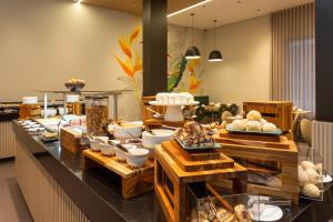a bakery with a buffet of bread and pastries at Hotel Roochelle Convention By Nobile in Curitiba
