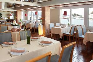 a dining room with tables and chairs and windows at Hotel Spa Cap de Creus in Port de la Selva