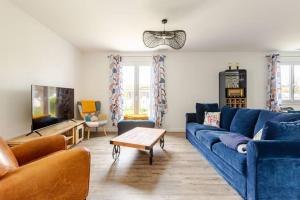 ChassironLa maison du Bout du Monde, Jacuzzi, Climatisation, 4 chambres, Plage à 600M et Phare à 1Km的客厅里有一张蓝色沙发和一台电视