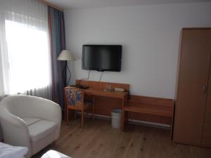 a hotel room with a desk and a tv on the wall at Hotel Fährhaus in Saarbrücken