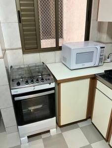 a kitchen with a stove and a microwave at Ape Av Brasil pertinho do mar in Balneário Camboriú