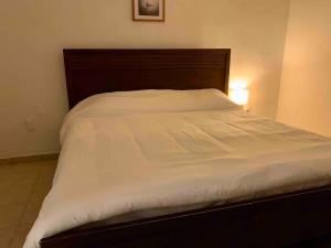 un letto con lenzuola bianche e testiera in legno di En el Malecon de Puerto Peñasco a Puerto Peñasco