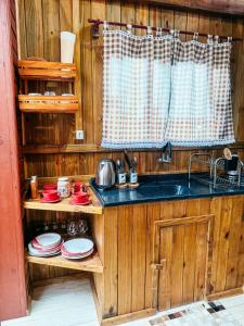 a kitchen with a sink and red dishes on shelves at Chalé Rústico com Hidromassagem e Piscina in Imaruí
