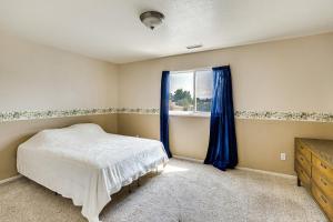 a bedroom with a bed and a window with blue curtains at Home with Backyard about 12 Mi to Grand Junction! in Fruita