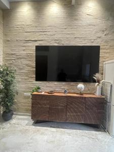 a large television on a brick wall with a table at Dream Big with jacuzzi and terrace in Ruzafa in Valencia