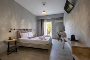 a bedroom with a bed and a desk and a television at California Beach Hotel - Adults Only in Laganas +46 photos