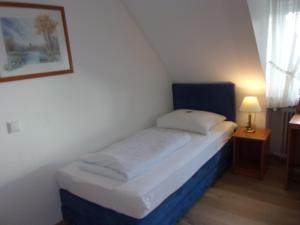 Cama pequeña en habitación pequeña con lámpara en Hotel Fährhaus, en Saarbrücken