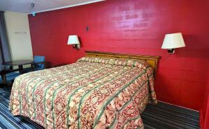 a bedroom with a bed with a red wall at Economy Hotel Dublin in East Dublin