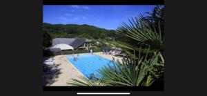 a view of a swimming pool with people sitting around it at Chalet climatisé dans un écrin de verdure in Lissac-sur-Couze