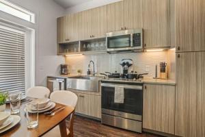 a kitchen with wooden cabinets and a table with chairs at Pampering New Unit Studio 1Ba Pool, Golf Sim in Austin