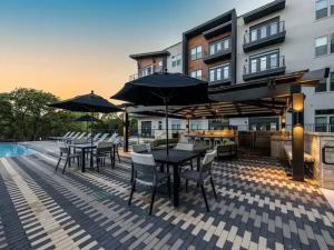 a patio with tables and chairs with umbrellas at Pampering New Unit Studio 1Ba Pool, Golf Sim in Austin