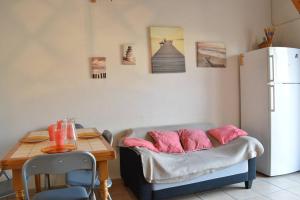 a kitchen with a table and a couch with pink pillows at SP190-119 Maison mezzanine 6 couchages SAINT PIERRE LA MER in Saint Pierre La Mer