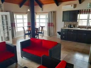 a living room with a red couch and a kitchen at Survivor Samoa Beach Resort in Falelatai