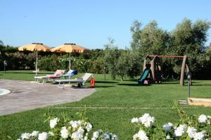 Agriturismo Il Lentisco في بولغيري: حديقة مع ملعب مع أرجوحة