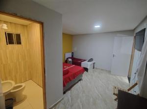 a bedroom with a red bed and a bathroom at Hotel Boneario in Vitória da Conquista