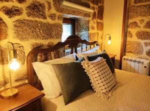 a bedroom with a wooden bed with pillows on it at Castrum Houses - Casa da Curveirinha - Jacuzzi in Melgaço +47 photos