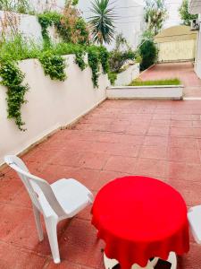 a red table and two white chairs on a patio at Jolie villa a Ennacer in Ariana +14 photos