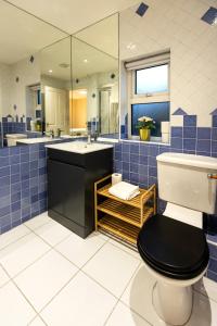 a blue tiled bathroom with a toilet and a sink at The Annadale - Luxury 3 bd House - Gold Short Term Stays in Belfast
