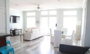a living room with a white couch and chairs at Beach Getaway at 2 Pelicans Walk to the Water in Crystal Beach